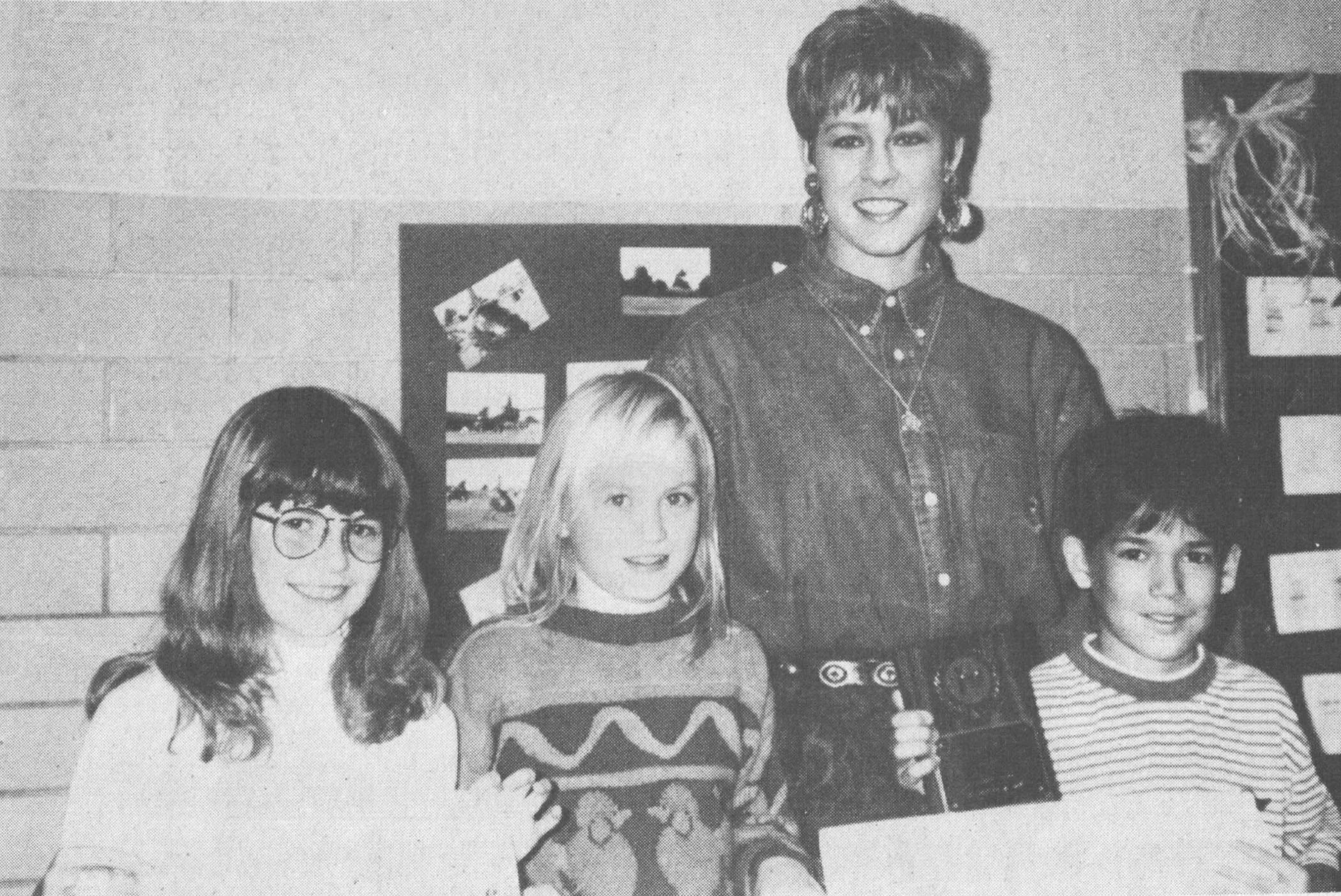 Lighted Christmas parade organizer Kelly Moody, center, presented plaques to poster contest winners and ribbons to secondand third-place winners. Winners from East Elementary were, from left, Jessica Wilson, third place, Erica Dow, second place, and Justin Pounds, first place. Original photo published December 7, 1993.